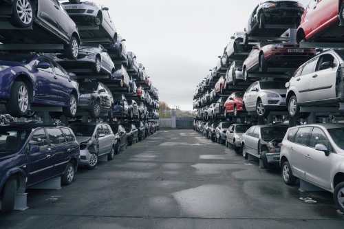 Vehicle dismantling yard with two rows of car racks, each storing four cars in height